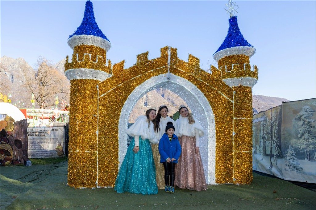 Bambino con le principesse davanti al castello luminoso alla Grotta di Babbo Natale di Ornavasso