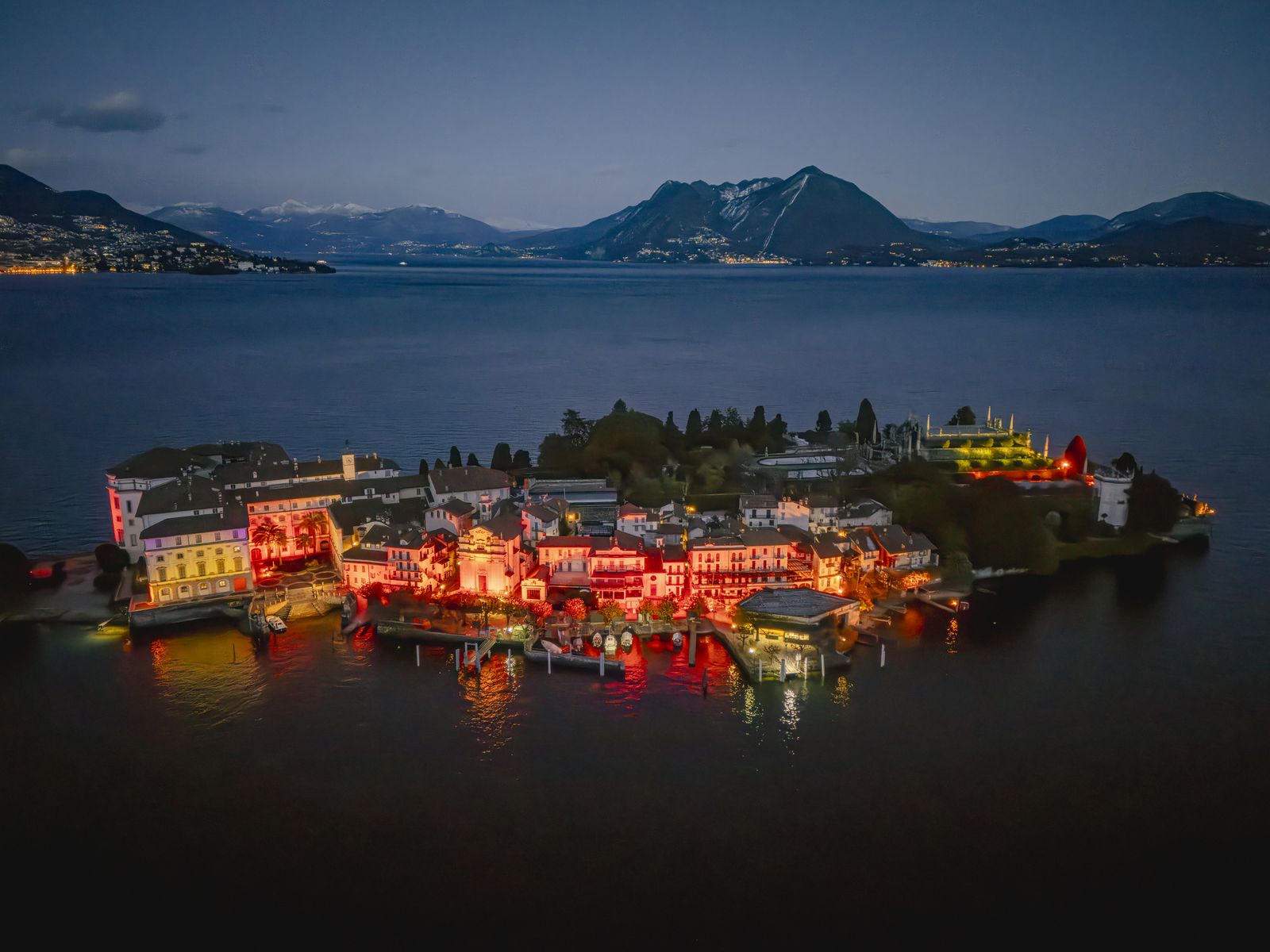 Isola Bella vista dal lago di notte, palazzo e giardini illuminati di rosso e oro per le Isole di Luce sul Lago Maggiore