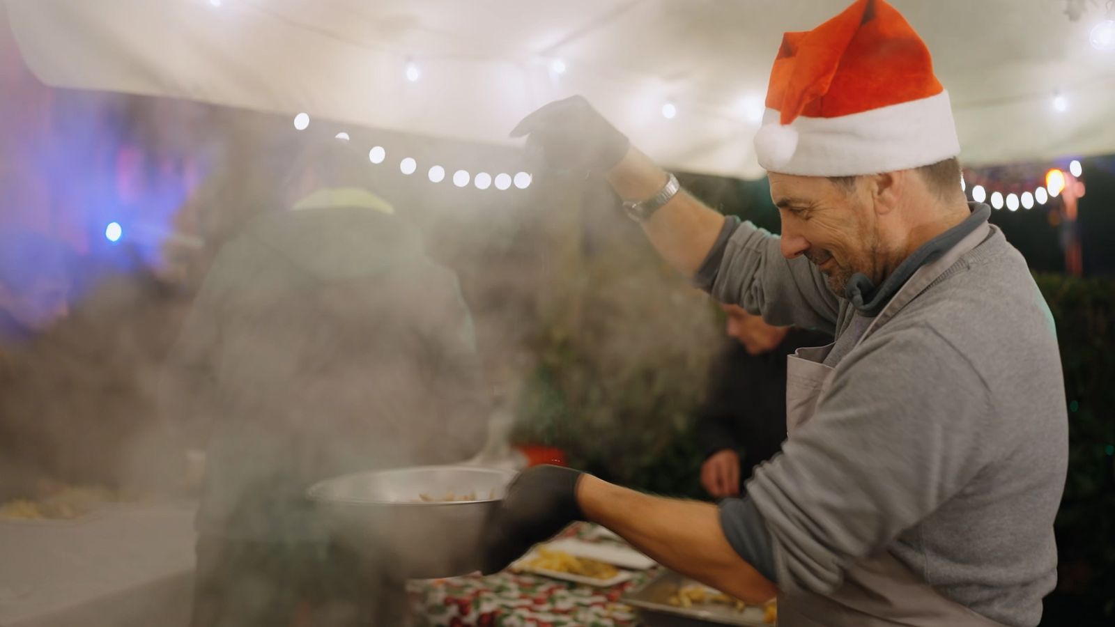Cuoco con cappello da Babbo Natale che prepara il piatto del pescatore al banchetto delle Isole di Luce, Isola Pescatori